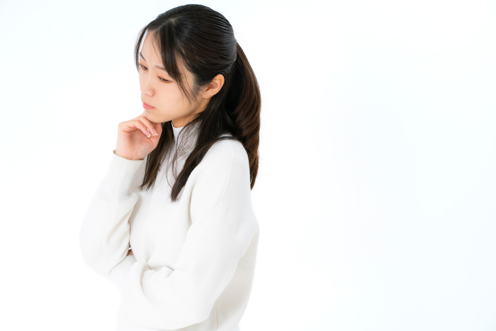 顎に手を添えて、次の進め方を考える白い服の女性のイメージ写真